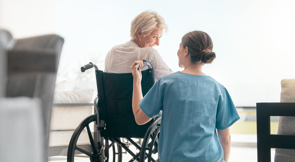 medicare service elderly woman in wheelchair smiling at nurse